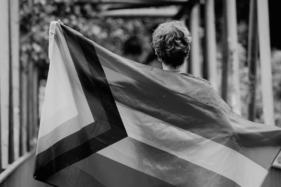 Person Holding a Progress Pride Flag Outdoors 